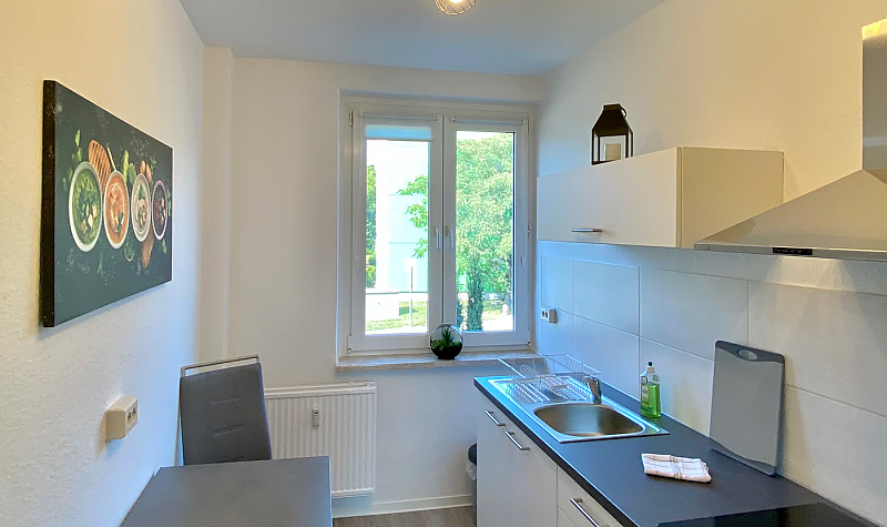 Moderne Küchenzeile mit Tisch, Stühlen und Wandbild