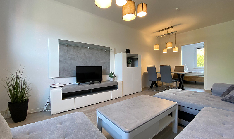 Gästewohnung mit Couchlandschaft und Medienwand sowie dezenter Beleuchtung