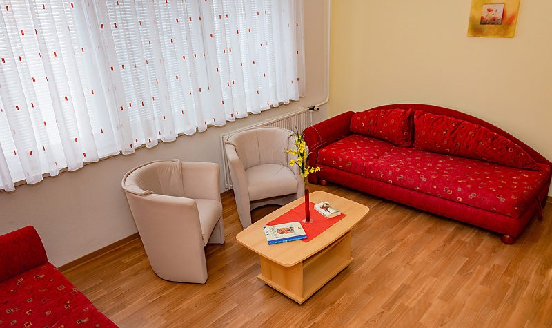 Gästewohnung Radebeuler Str. 6b - rote Couch mit weißen Sesseln und Clubtisch